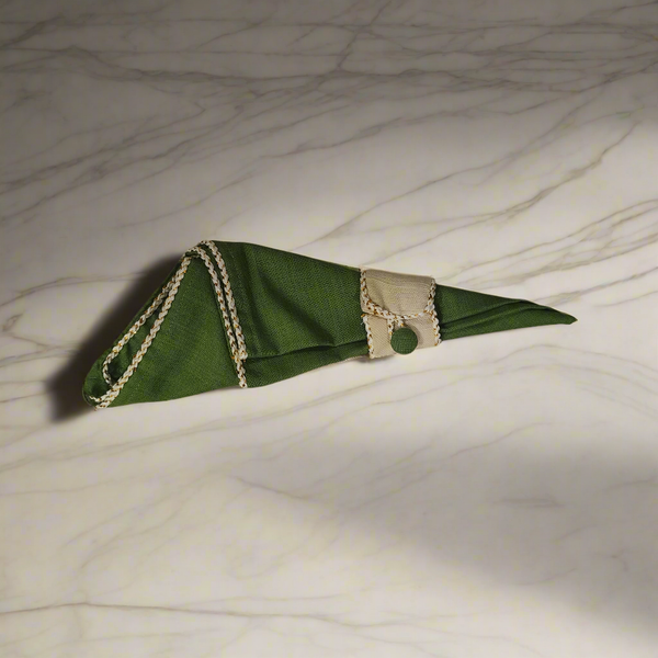 Green decorative napkin with ring featuring beige trim on marble surface