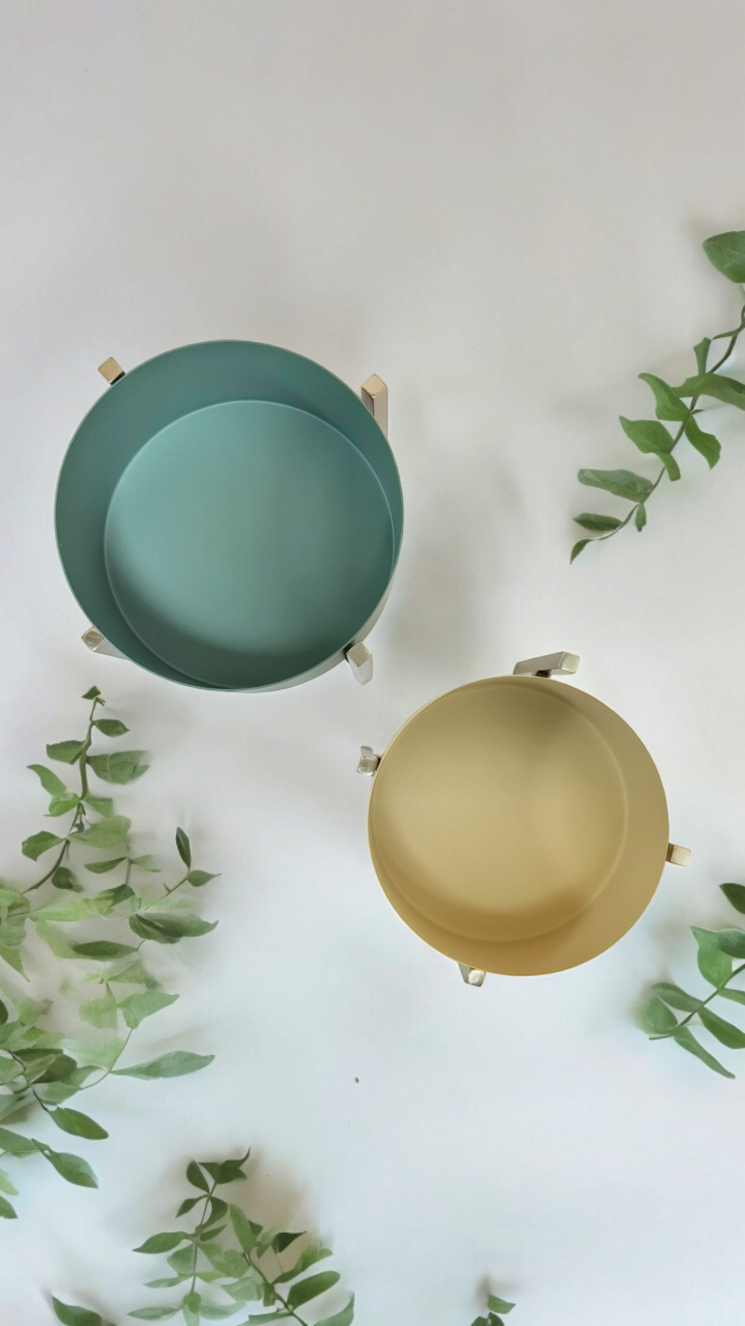 Detachable stand metal bowls in blue and yellow by Samaa India with green leaves background