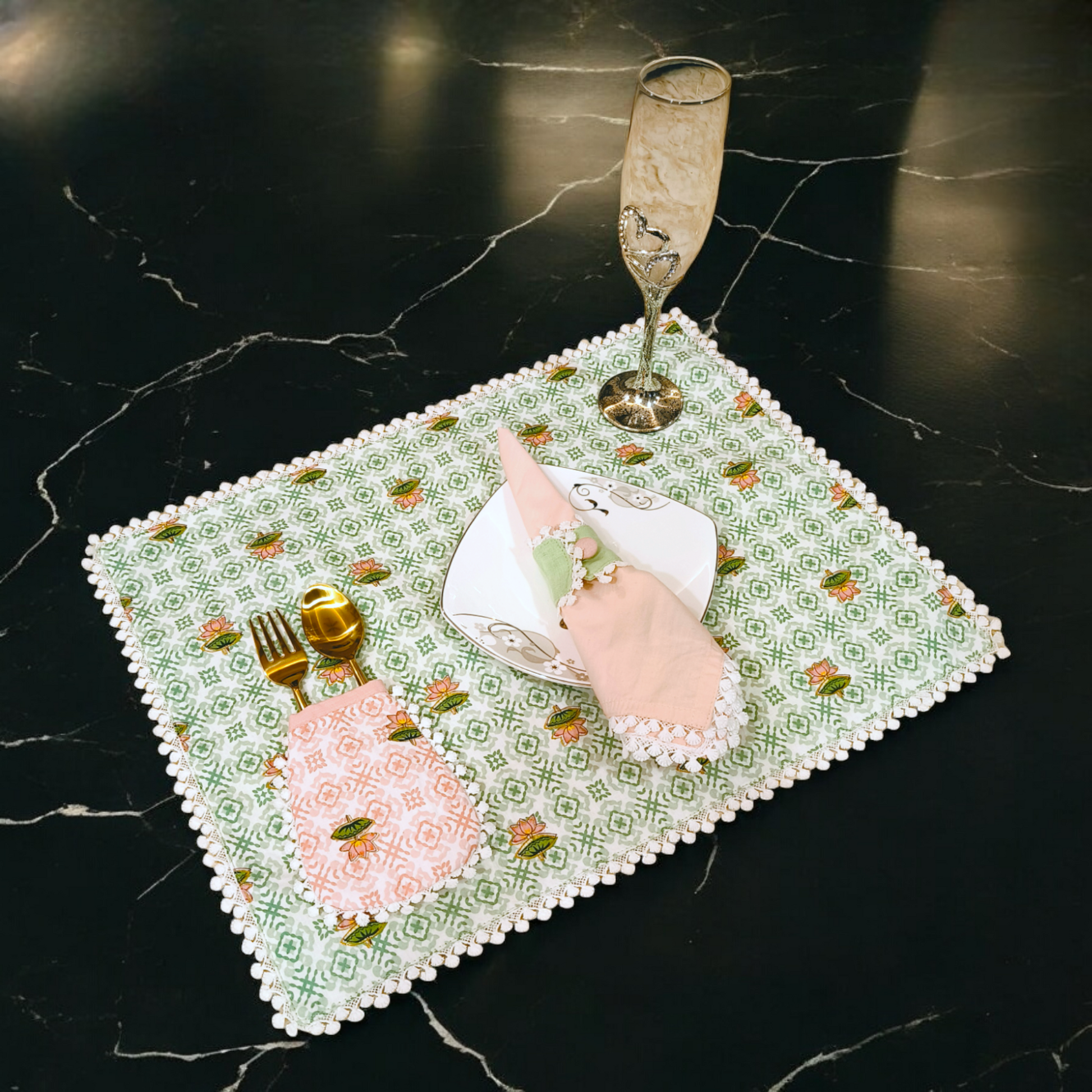 Elegant dining cutlery holders on a decorative green and white placemat with a glass and plate