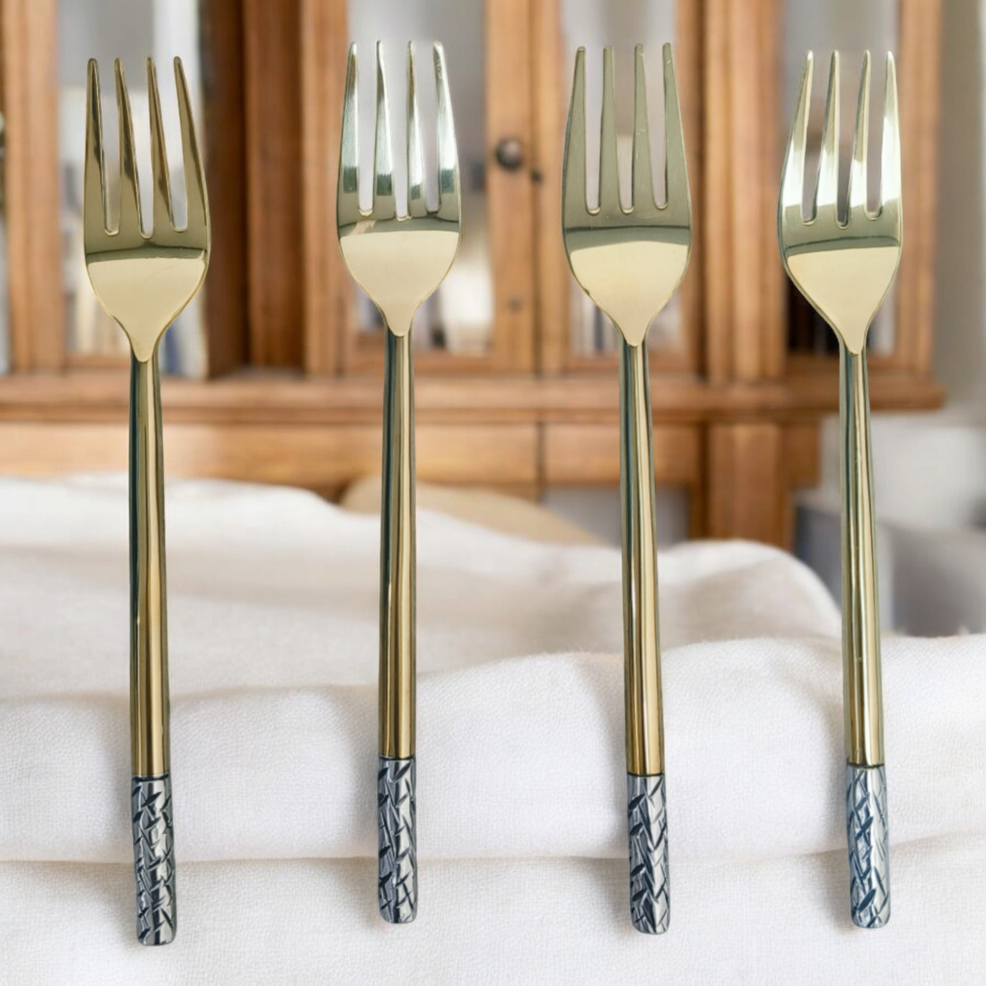 Samaa India luxury dinner fork set with gold finish and patterned silver handles on white fabric